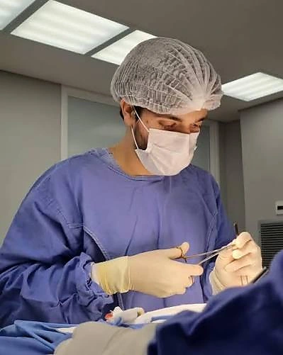 Dr. Rhael Rodrigues durante um procedimento cirúrgico, com paramentação e instrumentais